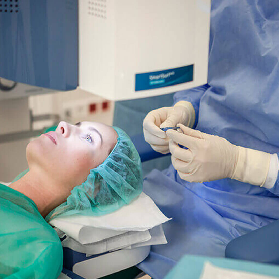 Frau liegt für Augenlaserbehandlung in Wien in OP-Bekleidung unter dem Augenlaser im Augenlaserzentrum Wien